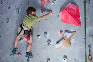 Gardinen little boy climbing a rock wall indoor. © altanaka
