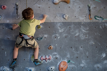 Fototapeta premium little boy climbing a rock wall indoor.