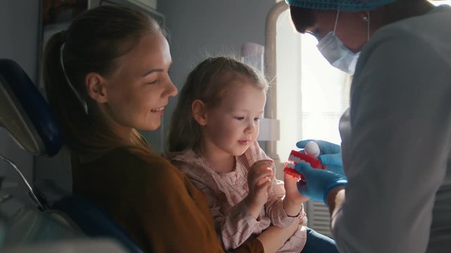 Girl, her mom and the dentist in the dental office, the stomatologist advising with a special toy