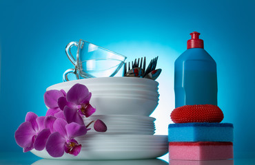 Set of clean dishes and Orchid flower, detergent, sponge, on blue