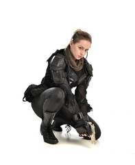 Fototapeta premium full length portrait of female wearing black tactical armour, crouching pose holding a weapon, isolated on white studio background.