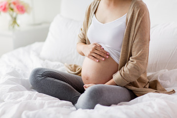 pregnant woman with bare belly sitting in bed
