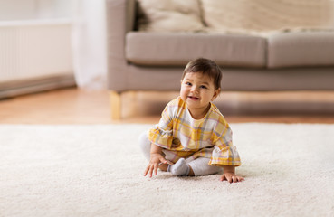 happy smiling baby girl sitting on floor home