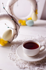 Easter composition, decorative wreaths and a cup of tea on a wooden table, a bright festive morning