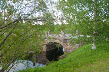 Fototapeta na wymiar Stone bridge across river in Park in early summer, Rovaniemi, Lapland region, Finland 