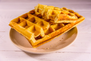 Ceramic plate with belgian waffles on wooden table