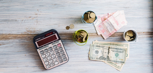 Calculator with money and pennies on a wooden green background. Business concept