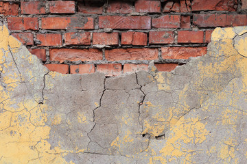 Cracked yellow paint on a brick wall.