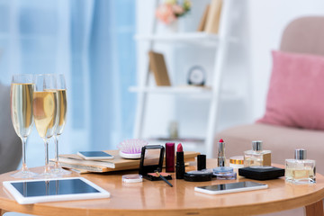 close-up view of gadgets, glasses of champagne and various cosmetics on table