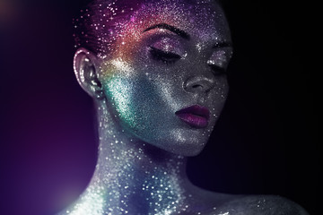 Portrait of Beautiful Woman with Sparkles on her Face. Girl with Art Make-Up in Color Light....