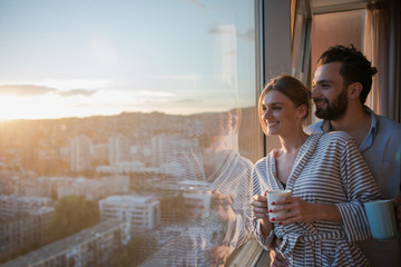 young couple enjoying evening coffee by the window