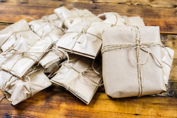 Close-up many gifts wrapped kraft paper on wooden background. One big present.