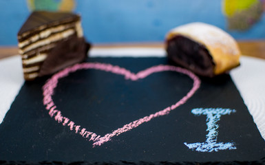 Different cakes on a stone plate with a heart painted on it.