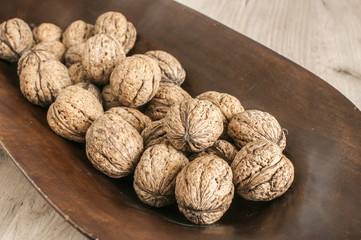 A pile of whole orgranic walnuts in shell closeup in wooden bowl
