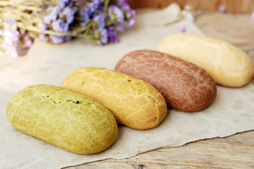 Close up of assorted eclairs (vanila, chocolate, coffee, pistachio) over wooden background. Soft focus.