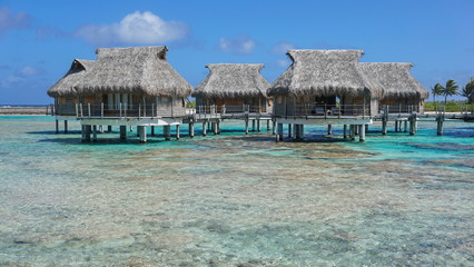 Tropical bungalows with thatched roof over the sea in the lagoon, Tikehau atoll, Tuamotus, French Polynesia, Pacific ocean, Oceania