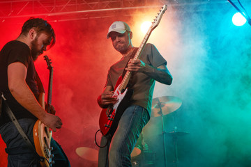 Rock band performs on stage. Guitarist, bass guitar and drums.