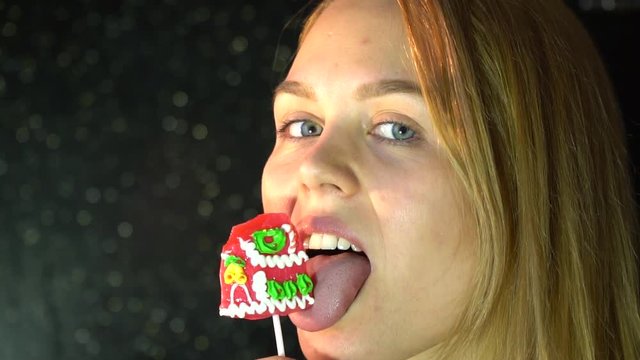 blonde woman licks a delicious sweet lollipop