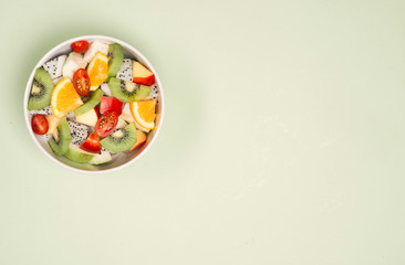 Bowl of healthy fresh fruit salad on wooden background. Top view.