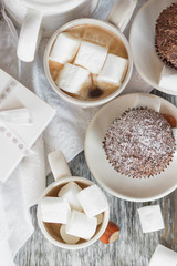 Cups with cacao and marshmallow, cupcakes and different decorations