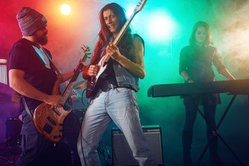 Rock band performs on stage. Guitarist, bass guitar and drums.