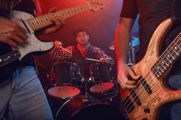 Rock band performs on stage. Guitarist, bass guitar and drums.