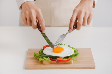 Hands of man cut the eggs on paper, served with bread, herbs, sausage and fresh juice.