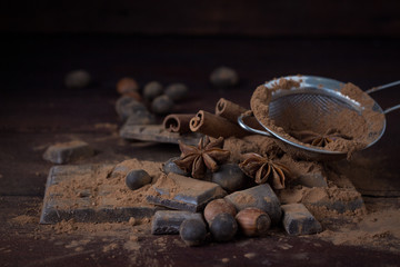 Chocolate, Spices, Spoon with Cocoa, Metal Strainer, Hazelnut on Dark Wood Background