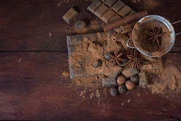 Chocolate, Spices, Spoon with Cocoa, Metal Strainer, Hazelnut on Dark Wooden Background. Copy space. Flat lay, top view