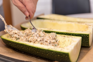 Mann füllt große Zucchini mit einer Füllung, gesunde Ernährung und Kochen