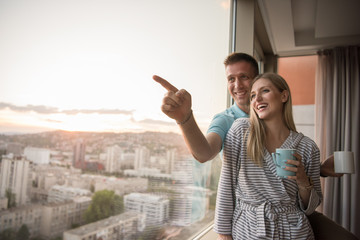 young couple enjoying evening coffee by the window