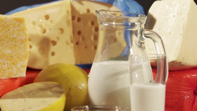 Cheese varieties. Different types of cheeses on wooden table. Stack of cheese wheels, balls and wedges on a dark background. Dolly shot