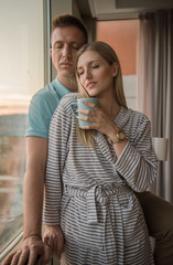 young couple enjoying evening coffee by the window