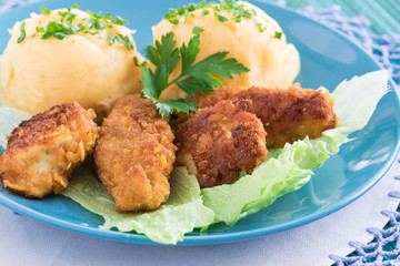 Chicken nuggets in crispy batter served on lettuce leaves with mashed potatoes
