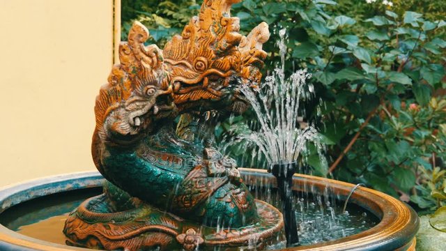 Three-headed green dragon as a traditional Buddhist symbol. Statue and a fountain of dragon in the garden of Thailand