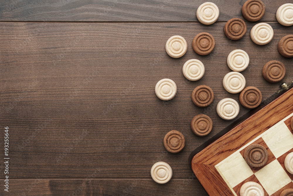 Wall mural top view of wooden draughts game on brown table background