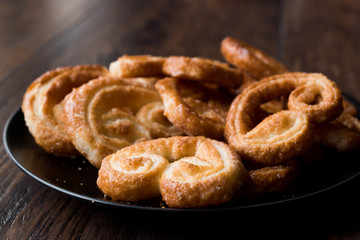 Palmier Cookies in Black Plate on Wooden Surface.