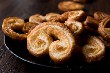 Palmier Cookies in Black Plate on Wooden Surface.