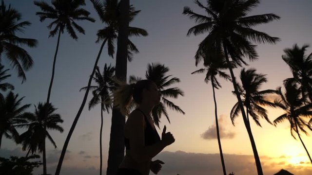 the girl runs around in the morning in the palm trees at dawn