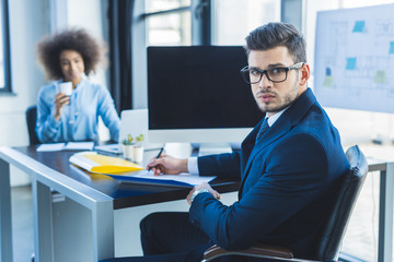 handsome businessman looking at camera in office