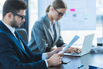 side view of businessman and businesswoman looking at documents in office