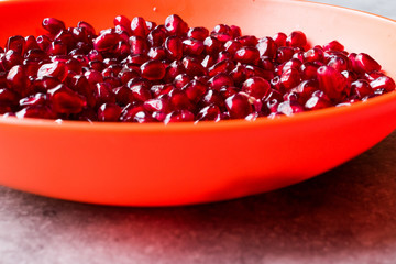 Organic Fresh Pomegranate Seeds in Red Bowl with Blue Background.