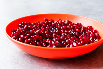 Organic Fresh Pomegranate Seeds in Red Bowl with Blue Background.