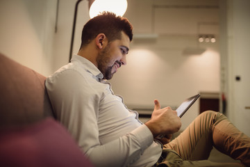 Young handsome man using tablet computer late at night.