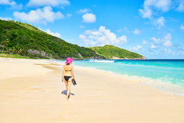 A woman tourist on tropical Beach Police Bay (white sand and turquoise sea) , south of Mahe, Seychelles