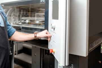 Man operating offset machine pushing the button at the printing manufacturing. Close-up view