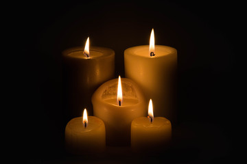 Fototapeta na wymiar Set of three burning candles against a dark background