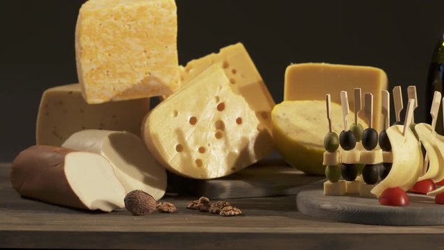 Cheese and wine tasting. Different types of cheese wedges, cheese skewered appetizers, and glasses with red wine on wooden table. Dolly shot