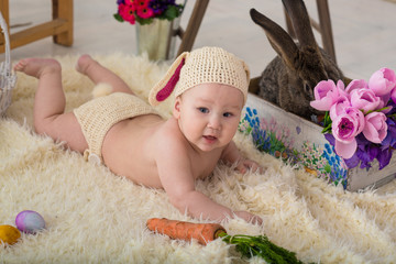 little boy in rabbit costume lays in flowers and easter rabbit
