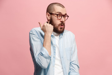 The young man whispering a secret behind her hand over pink background